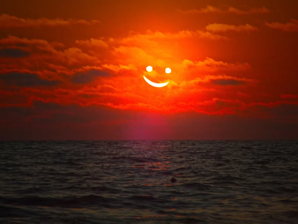 Zdjęcie zachodzącego słońca, gdzie słońce jest przedstawione jako uśmiechnięta buzia. Melanoma malignum jest rakiem zależnym od ekspozycji na UV.