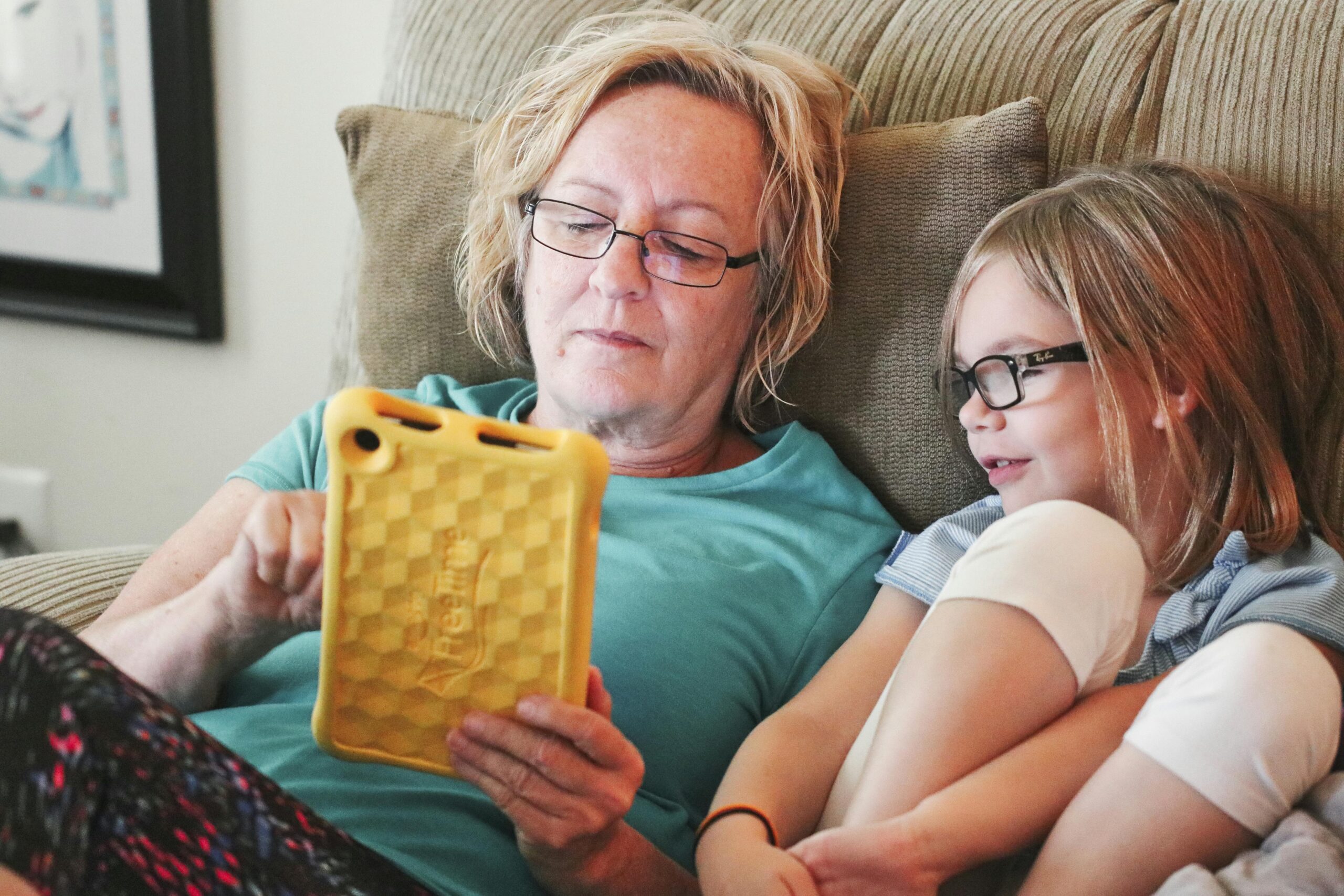 A grandmother and granddaughter enjoying a quiet moment together using a tablet.